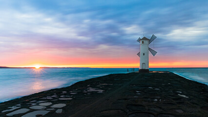 Stawa Młyny lighthouse in Świnoujście, Poland, on the shore of the Baltic Sea. A lighthouse in the shape of a mill at sunset.
