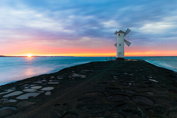 Stawa Młyny lighthouse in Świnoujście, Poland, on the shore of the Baltic Sea. A lighthouse in the shape of a mill at sunset.