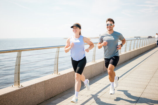 Couple jogging along seaside pathway enjoying healthy lifestyle