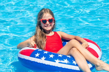 Happy smiling little girl 7-8 years old in red swimsuit and sunglasses relaxing in outdoor swimming...