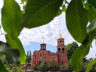 red brick temple with two golden domes. Church on a cloudy summer day