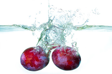 Fresh Plums Splashed into Clear Water Creating Beautiful Bubbles
