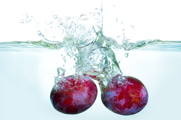 Fresh Plums Splashing in Clear Water Creating Dynamic Ripples