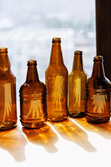 Amber glass bottles lined up by window casting strong golden reflections and deep shadows