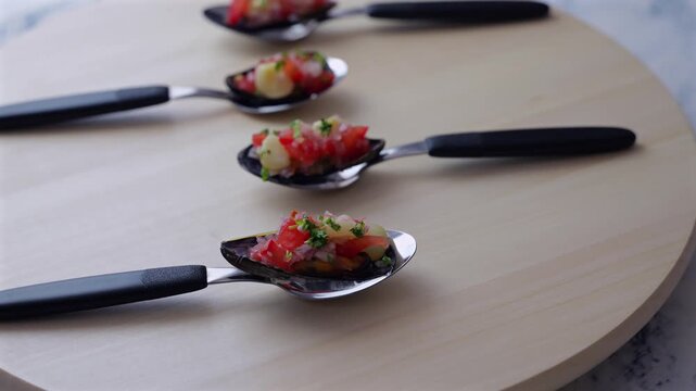 Spoons with typical Peruvian appetizers displayed on a wooden tray.