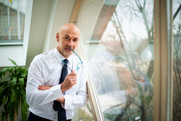 Shot of a middle aged businessman using a digital tablet while standing at a window in an offic