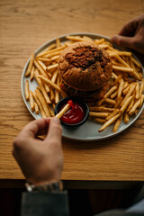 Businessman dipping french fries in ketchup with a burger on a plate