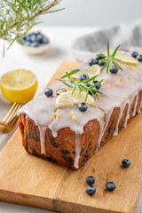 Homemade blueberry lemon loaf cake on a wooden board on a light background with fresh berries