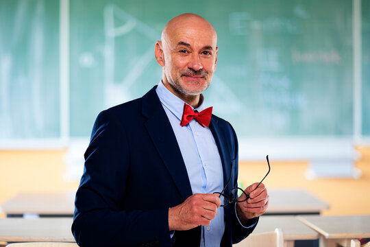 Portrait of senior male professor standing in front of chalkboard at school - Powered by Adobe