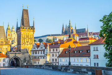 Obraz premium Dawn breaks over Charles Bridge in Prague, illuminating the stunning architecture and historical landmarks. The quiet river Vltava reflects the warm hues of morning light.
