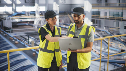 Employees Working at a Modern Logistics Center for an International Online Shopping Platform. Female and Male Managers Using a Laptop Computer to Optimize the Deliveries