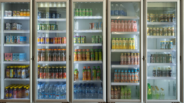 Variety of bottled and canned drinks neatly arranged in a commercial refrigerator at a store, featuring juices, teas, milk, and mineral water on july 11,2025 in padang,indonesia