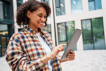 A Young Woman Engaged with a Tablet While Enjoying the Outdoors in an Urban Environment