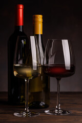Wine glasses filled with wine beside a bottles