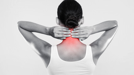 Rear back view of tired young woman touching inflammated zone on her neck, suffering from cervical...