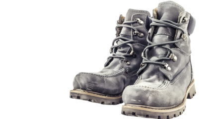 A pair of worn leather work boots with laces and metal eyelets on an isolated dark surface