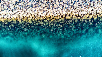 Aerial view of turquoise waters meeting the rugged, sun-kissed rocky shore, a dance of textures and tones where the land embraces the sea., Split, Split-Dalmatia County, Croatia.