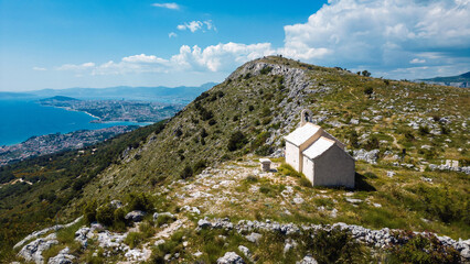 Aerial view of a stone chapel atop a rugged peak overlooking the cityscape and the Adriatic Sea, Split, Split-Dalmatia County, Croatia.