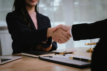 A professional businesswoman sits at her desk writing in a notebook, focused and thoughtful, surrounded by legal tools, documents, and a laptop in a modern office.