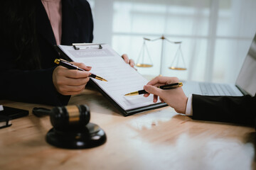 A lawyer consulting with a client in an office, reviewing legal documents and contracts related to...