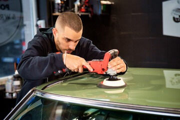 A young man polishing an old-timer car in his garage