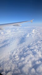 Airplane Wing Above the Clouds with Clear Blue Sky, Cloudscape Seen from Commercial plane in Flight, travel background