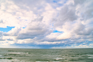 Blue sky with clouds over the sea. Calm landscape on the theme of travel and seaside recreation.