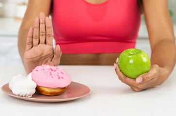 Eat Less Sugar Concept. Close up of black girl giving up eating cake, choosing healthy tasty green apple