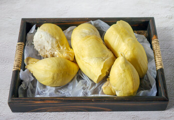 A yellow durian that has been peeled off to reveal the tasty yellow flesh of the durian. Durian fruit on wooden basket