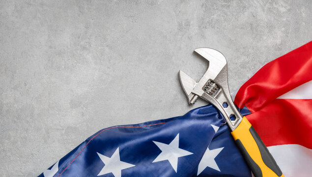 adjustable wrench and American flag on concrete. labor day concept