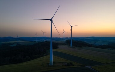 Obraz premium Wind turbines at sunset in a serene landscape.
