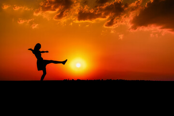 Silhouette of a Joyful Woman Jumping at Sunrise in a Summer Sky