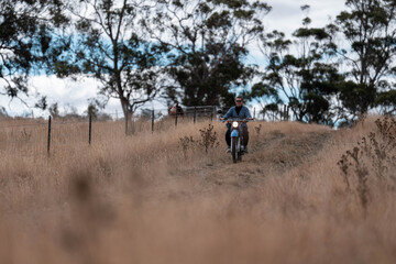 working in agriculture. girl riding a motorbike on a farm in outback Australia. Ranch worker...