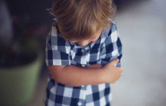 Close-up of an unhappy Boy standing with his  arms crossed and head down sulking