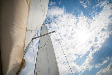 Full white sails blown by the wind against blue sky during sailing near Croatia. Symbol of movement, freedom and summer maritime journey.