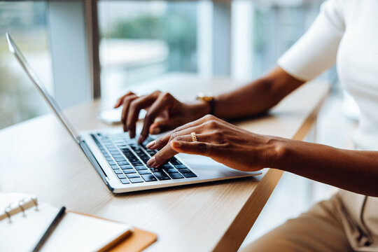Person typing on a laptop at a desk during the day