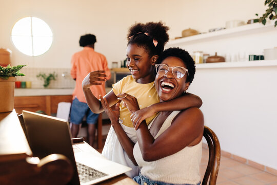 Working mom laughing happily with her daughter while working from home - Powered by Adobe
