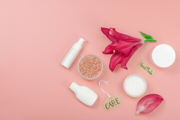 Skincare cosmetics concept with red lily on soft pink background, flat lay. Natural selfcare