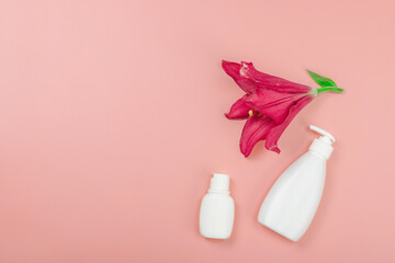 Skincare cosmetics concept with red lily on soft pink background, flat lay. Natural selfcare