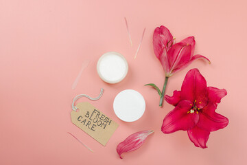 Skincare cosmetics concept with red lily on soft pink background, flat lay. Natural selfcare