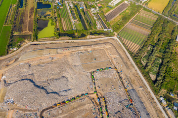 Aerial top view of A Huge Waste, garbage, dump, rubbish landfill. A landfill compactor, group of workers sort out the garbage in the landfill. Trash trucks dump waste polluting products. Pollution.