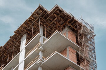Frontal view of a residential building under construction highlighting scaffolding and unfinished structure