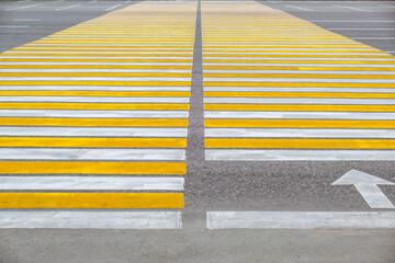 bold yellow and white stripes mark pedestrian crosswalk on busy urban street. clear lines guide foot traffic safely across asphalt during daytime. close up.