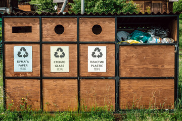 three recycling bins stand in outdoor park clearly labeled for paper, glass, and plastic. bins overflow with various recyclable materials, promoting sustainability. close up.