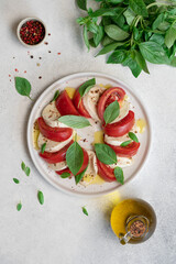 Fresh Caprese Salad with Mozzarella Cheese, Ripe Tomatoes, and Green Basil Leaves on White Background. Healthy Mediterranean Food Concept