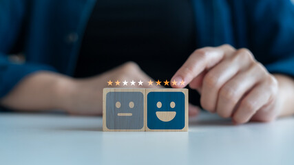 Close-up of hand giving star rating above sad and happy face blocks, symbolizing customer satisfaction, user experience, feedback system, and service quality review.