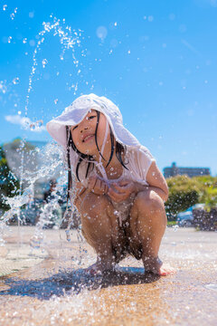 夏の日差しの中で噴水で水遊びを楽しむ子ども