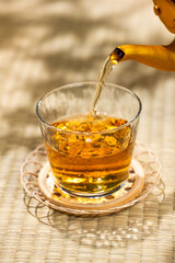 畳の上でやかんから麦茶をグラスに注ぐ和の涼を感じる夏