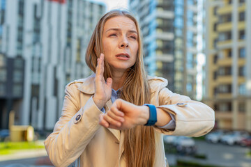 Scared mature businesswoman worrying to be punctual, with anxiety checking time on watch, running...