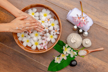 Spa Hand Soak, Relaxing foot spa treatment with herbal compresses, oils, and frangipani flowers in a serene wooden setting.
